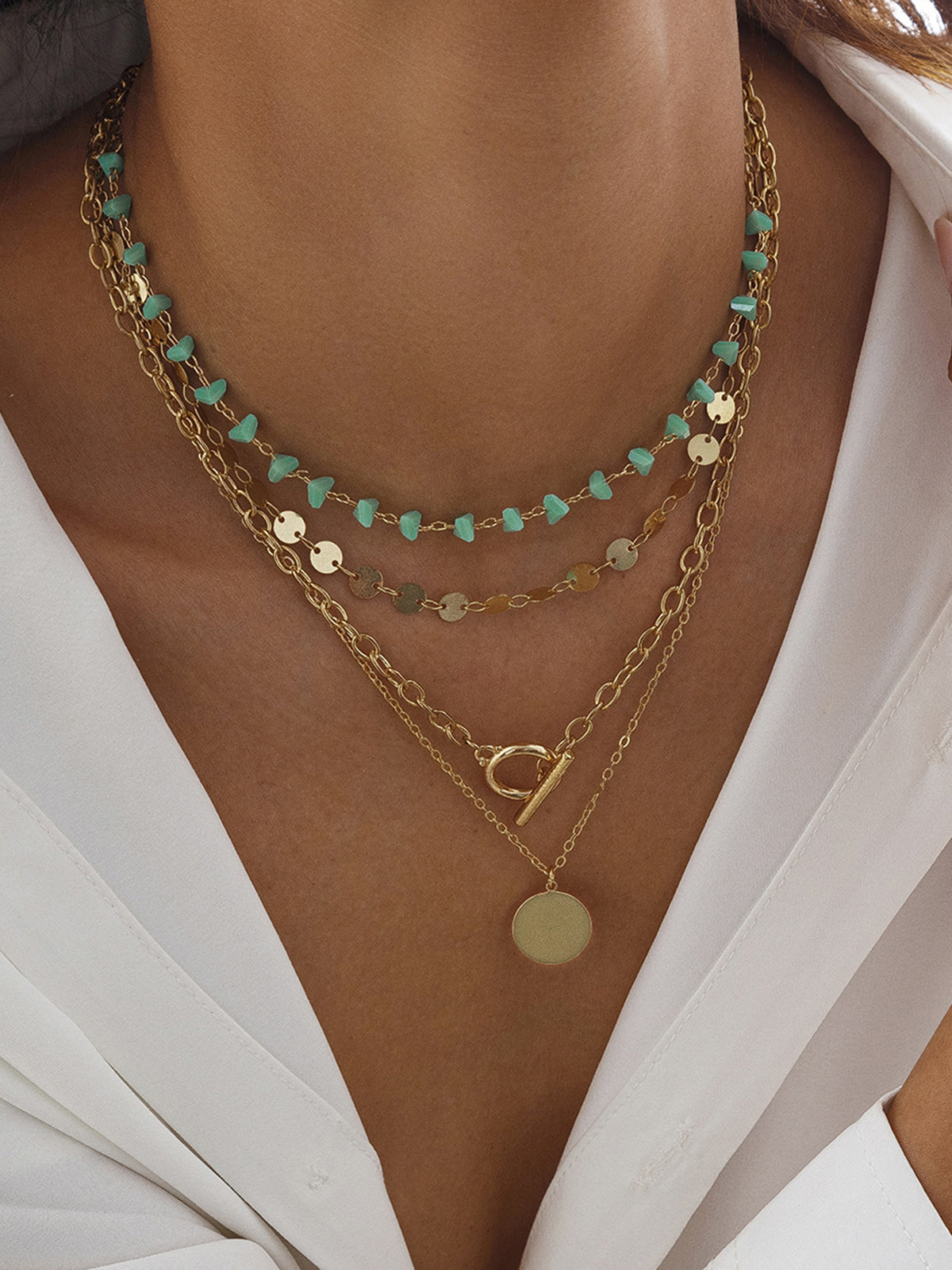 Collier multi-rangs chaîne dorée, perles turquoise et pendentif circulaire