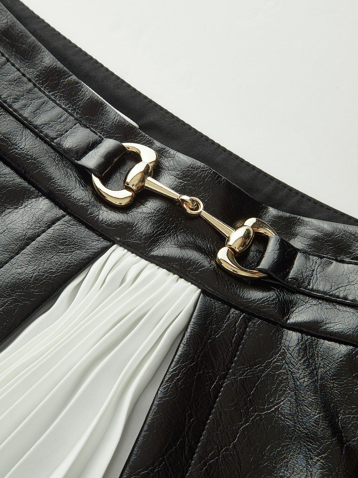 Kontrastfarbener Faltenminirock aus Kunstleder