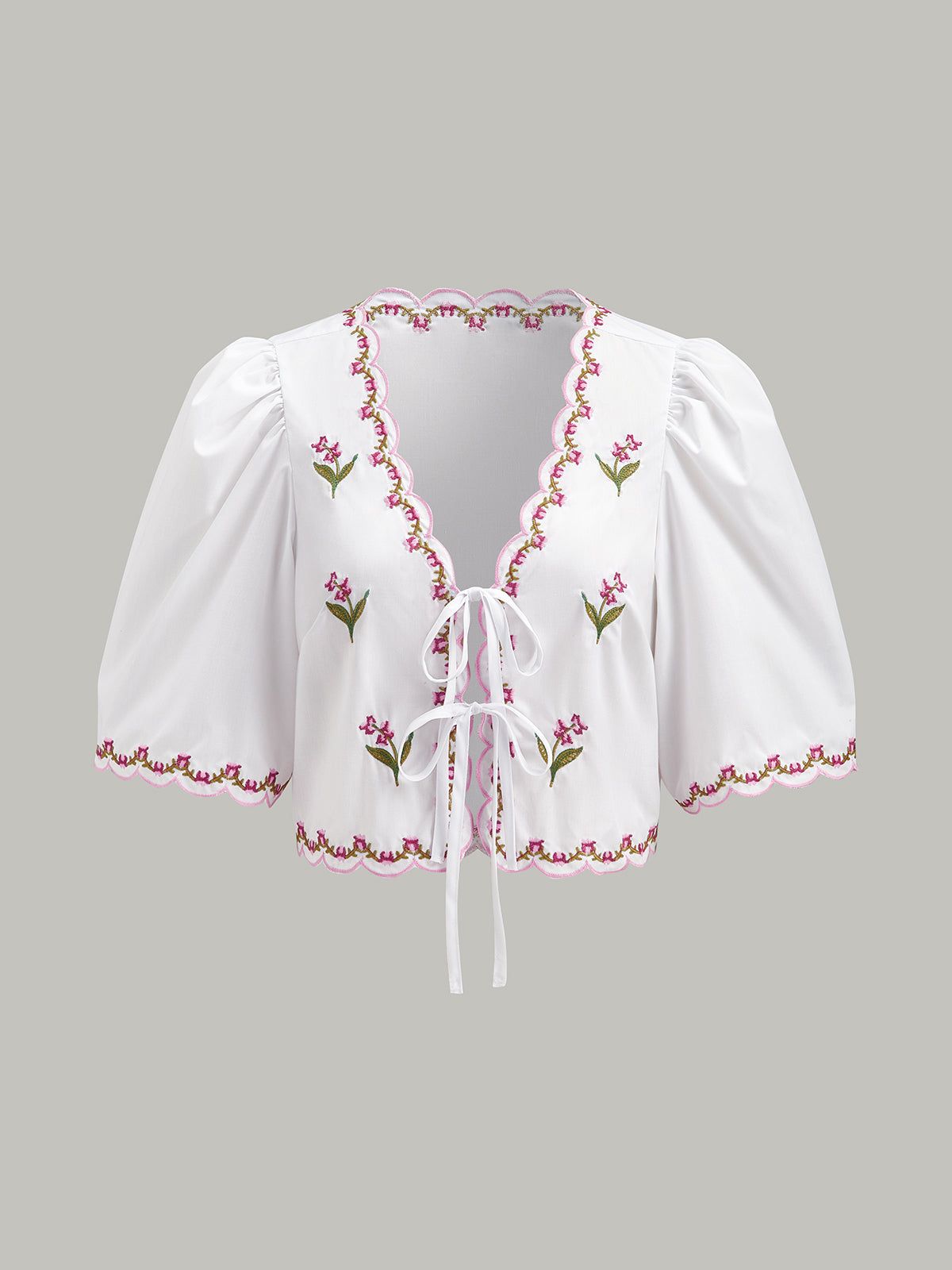 Blouse brodée à manches bouffantes et nœud, ornée de festons et de broderies. 
