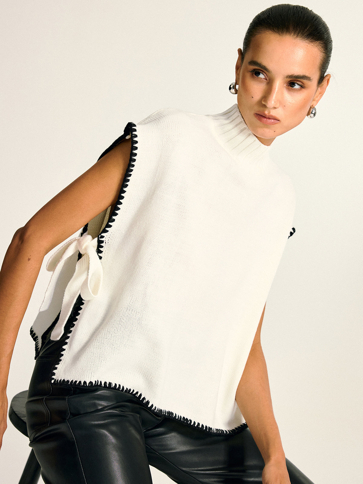 Strickweste mit kontrastfarbenem Zierbesatz, seitlicher Schleife und Stehkragen 